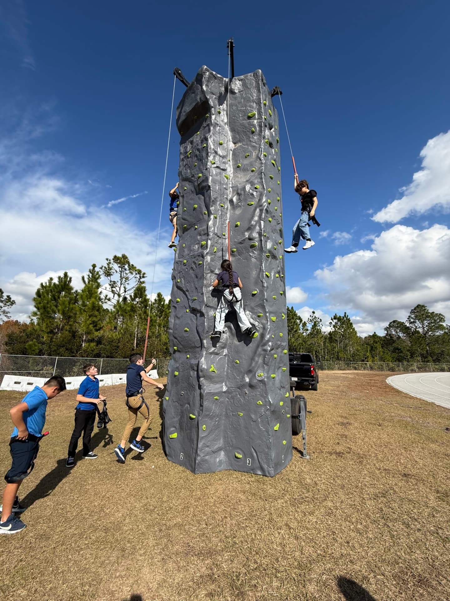 Three students climbing the mobile rock climbing tower