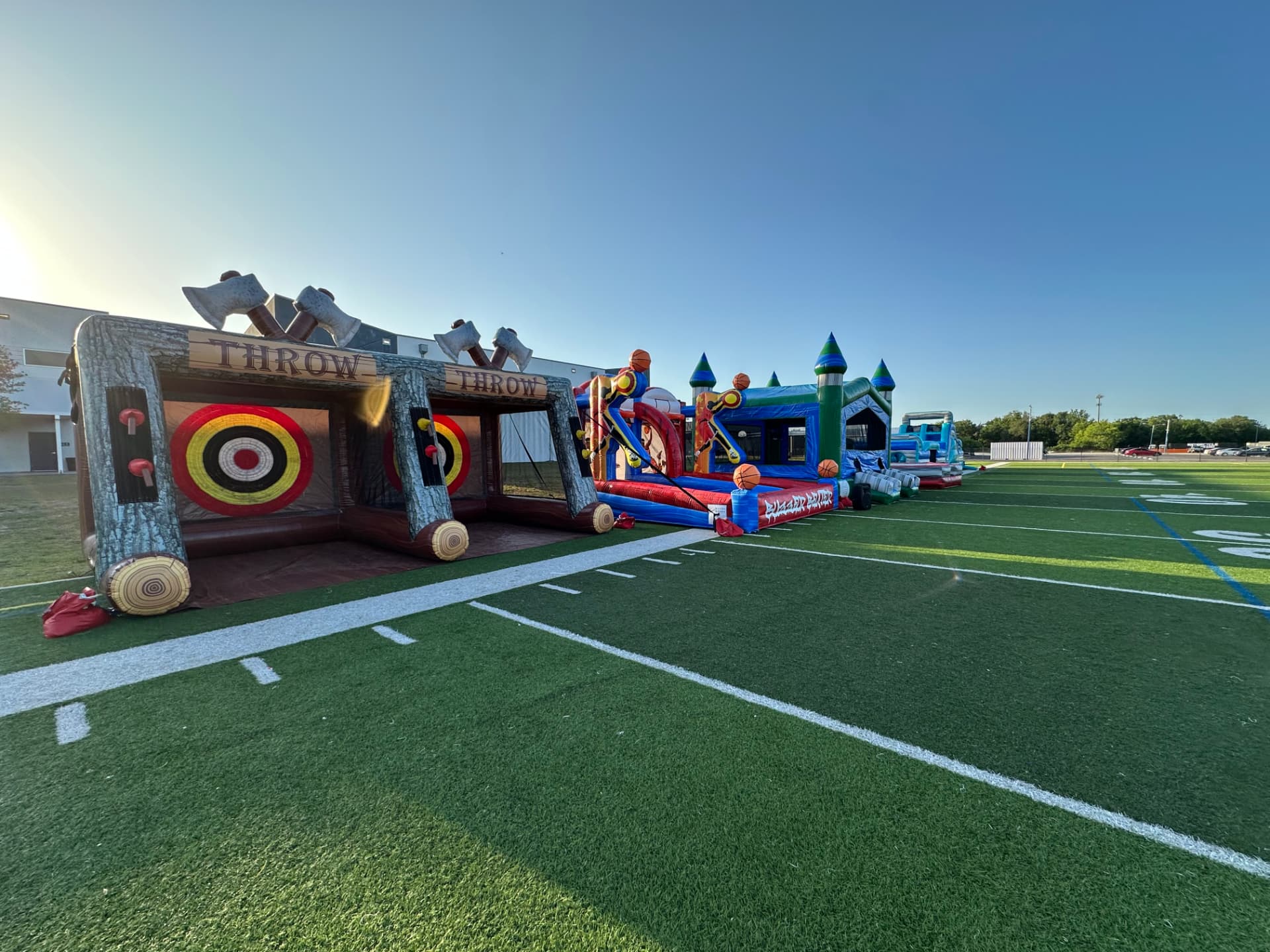 Inflatable axe throw game and bounce houses on a turf field