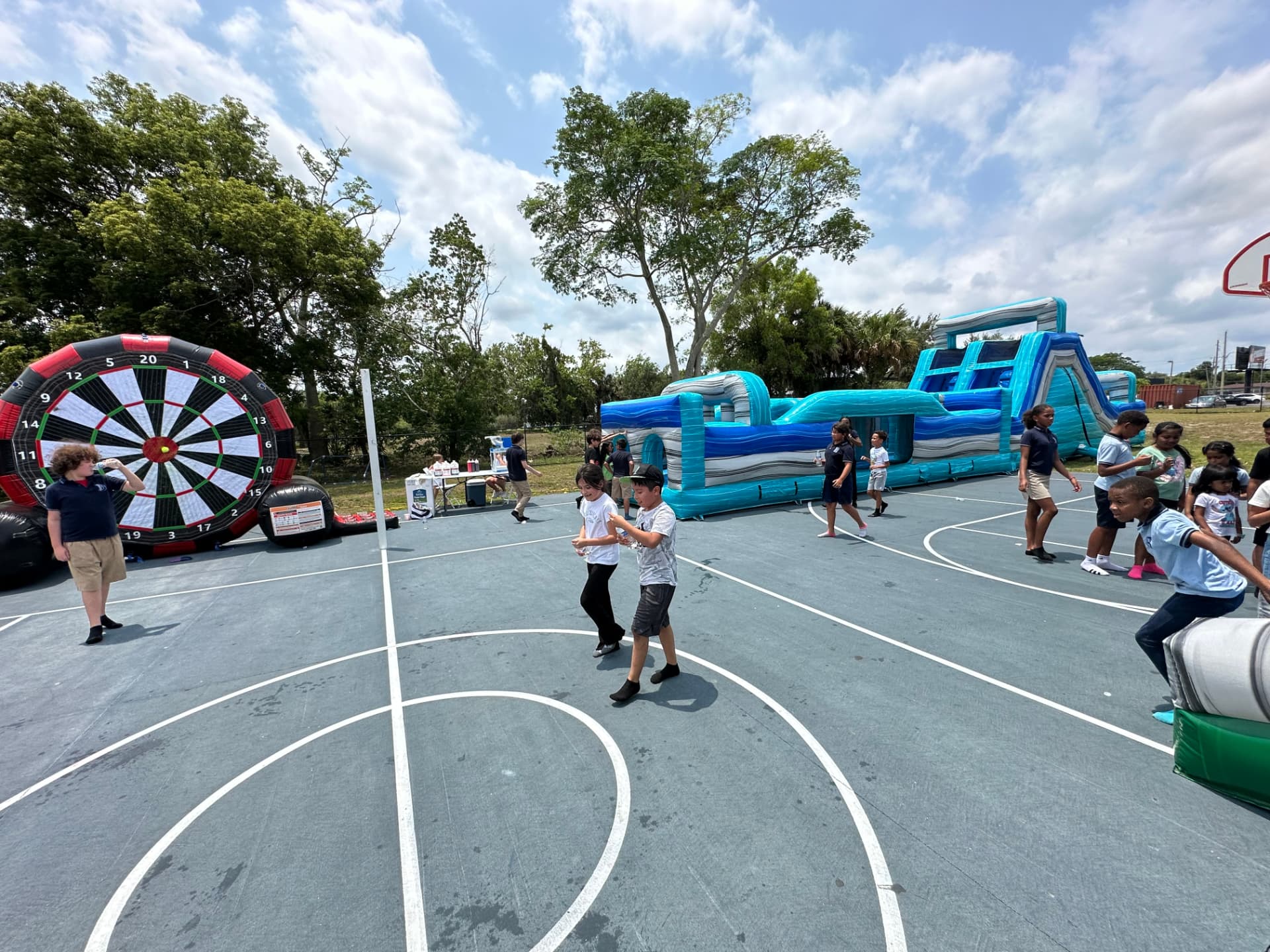 Students running past a large inflatable obstacle course and soccer dart board